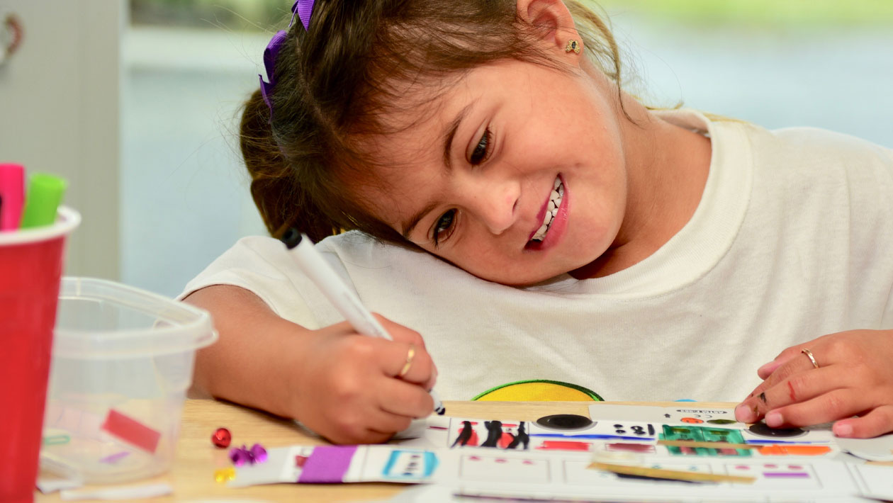 girl coloring at her desk with her head tilted